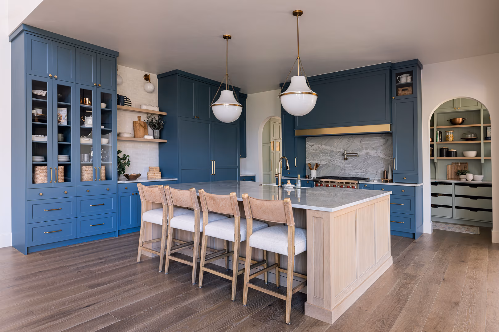 Perry home kitchen with blue cabinetry, a light oak island and white globe pendants