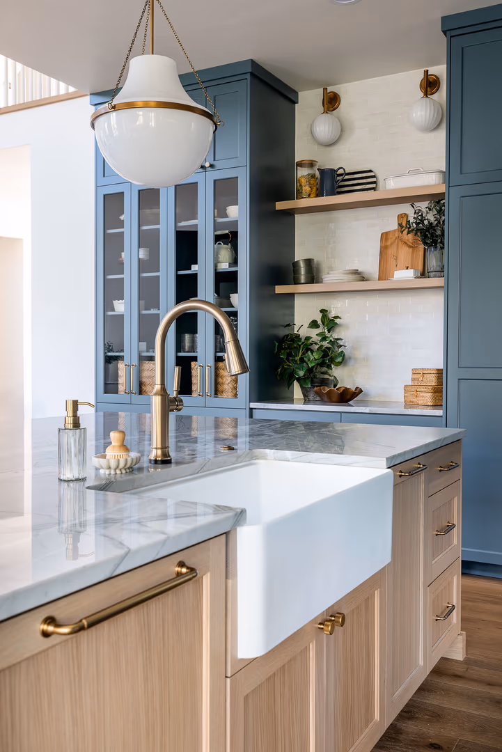 White farmhouse sink and brass faucet in the light wood island of the Perry kitchen