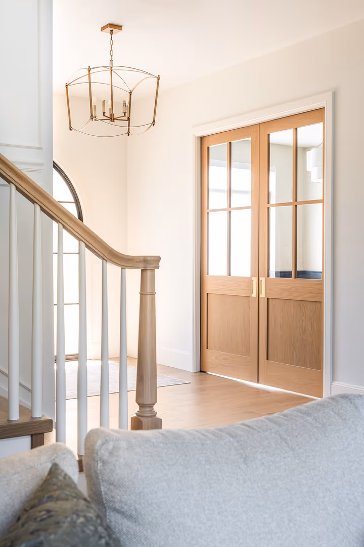 Wood glass-paneled double doors and a stair rail in the Perry home entry