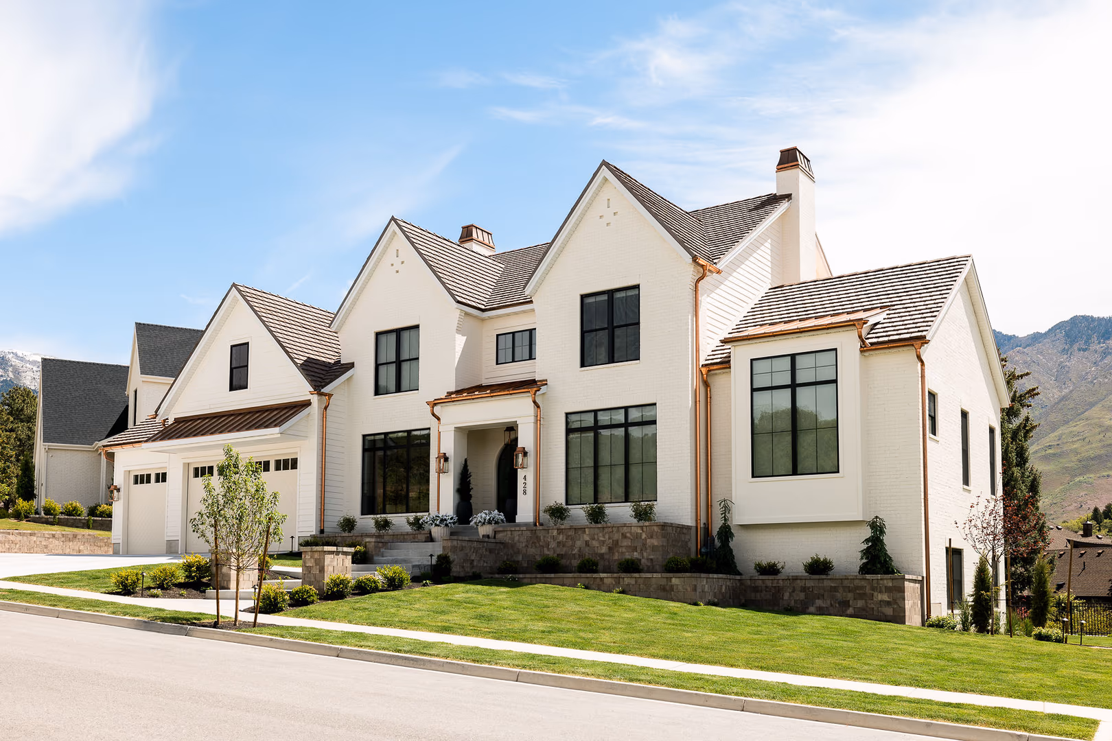 Perry home from the street, showing white brick gables, black windows and copper gutters
