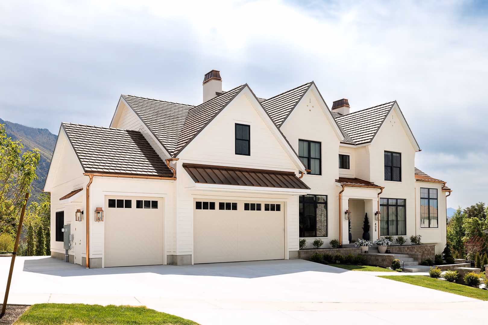 Garage side of the Perry home with white doors under copper roof awnings