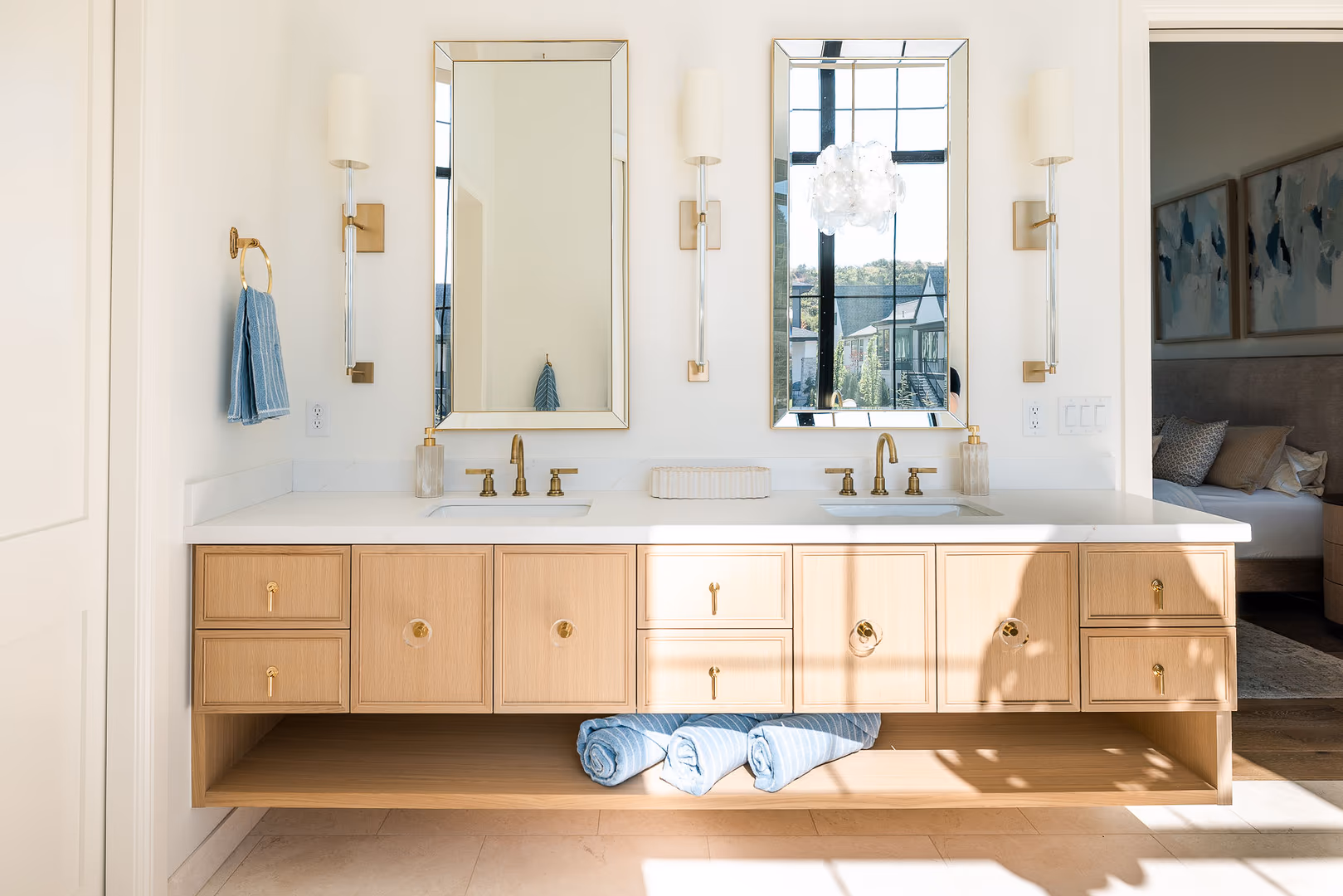 Floating light wood double vanity with brass faucets and tall mirrors in the Perry home