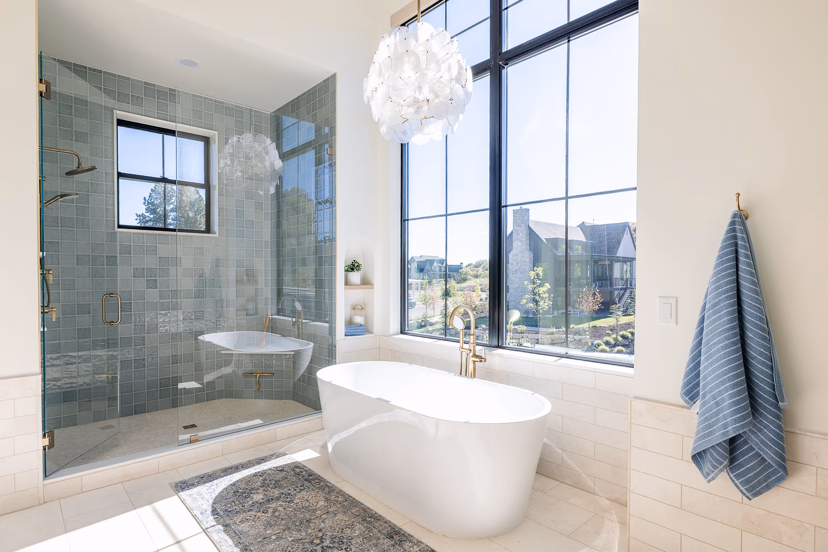 Perry primary bathroom with a freestanding tub, blue tile shower and tall black windows