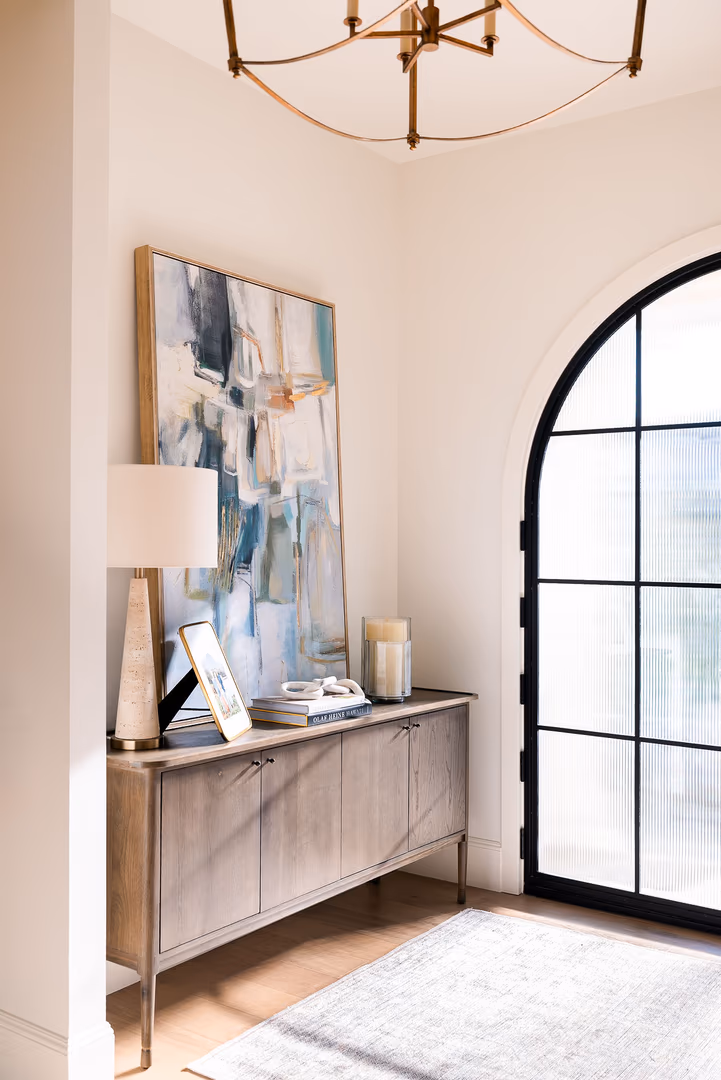 Entry corner in the Perry home with an arched black steel door and a wood console