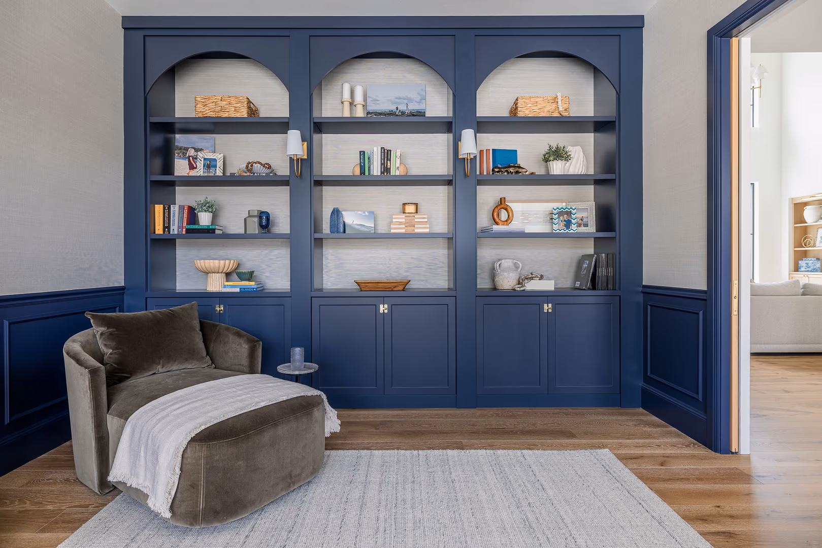 Navy built-in bookcase with three arched niches and a velvet chaise in the Perry home