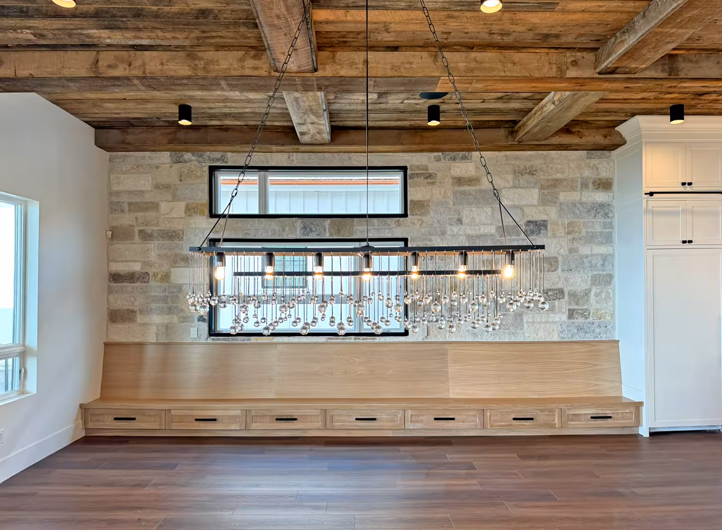 Dining area in the Plymouth home with a crystal chandelier, wood plank ceiling and a built-in bench