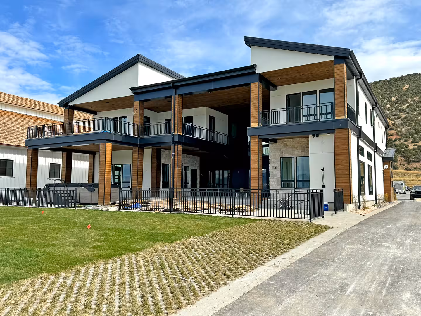Plymouth home with two stacked covered decks, wood columns and black railings beside a lawn