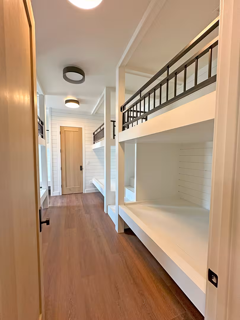Plymouth home hallway lined with built-in white bunk beds and black rails