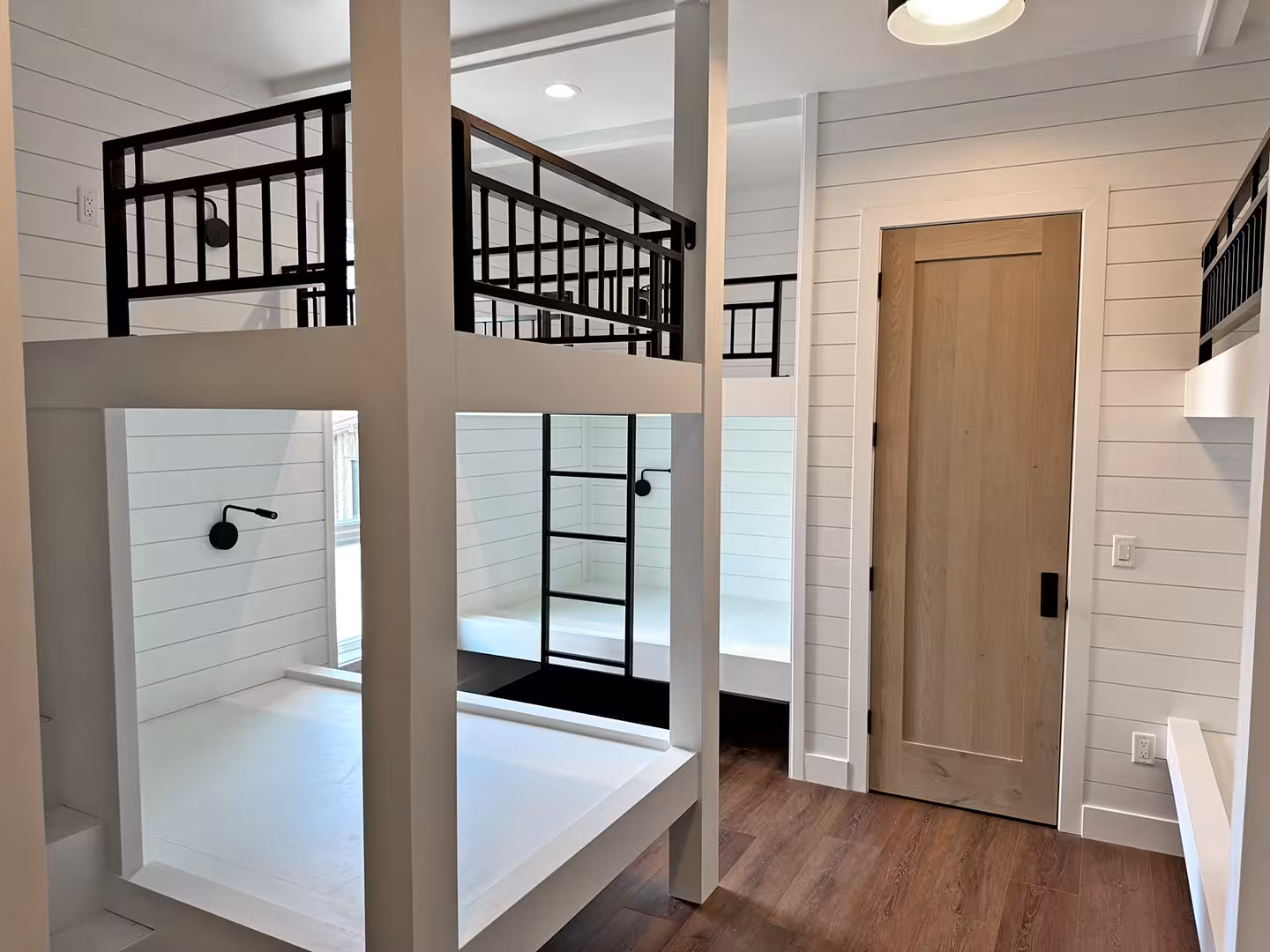 White built-in bunk beds with black railings and shiplap walls in the Plymouth home