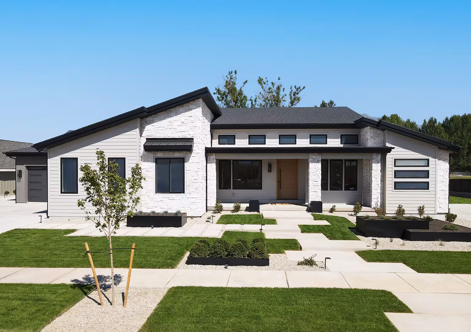 Front of the Rockville home with white stone, light siding and steel planter beds