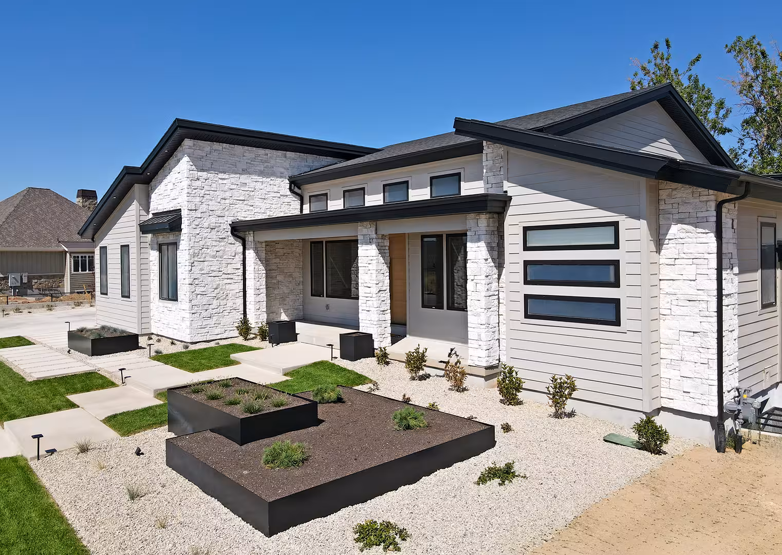 Rockville home entry with white stone pillars, a wood front door and raised steel planters