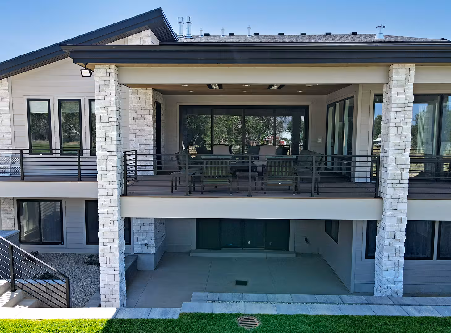 Covered back deck of the Rockville home with stone columns above a walkout patio
