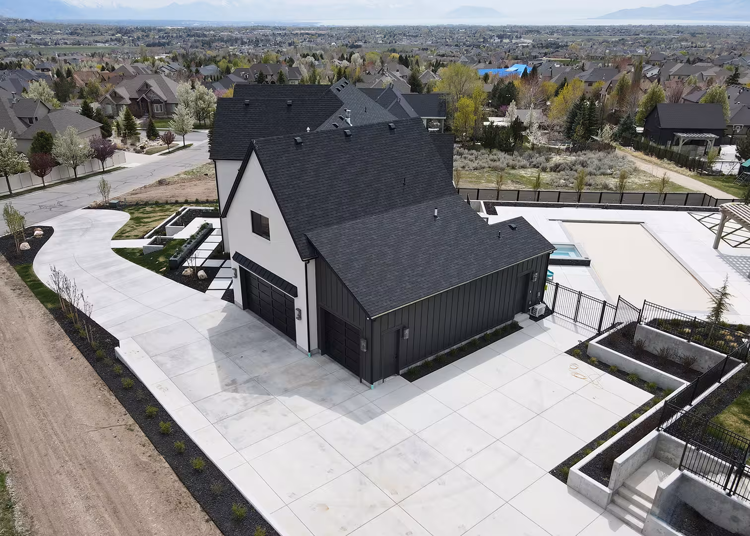Aerial view of the Syracuse home with its black garage wing, driveway and pool