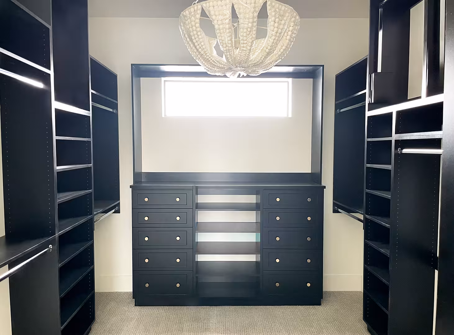 Walk-in closet in the Syracuse home with black built-in shelving and a beaded chandelier