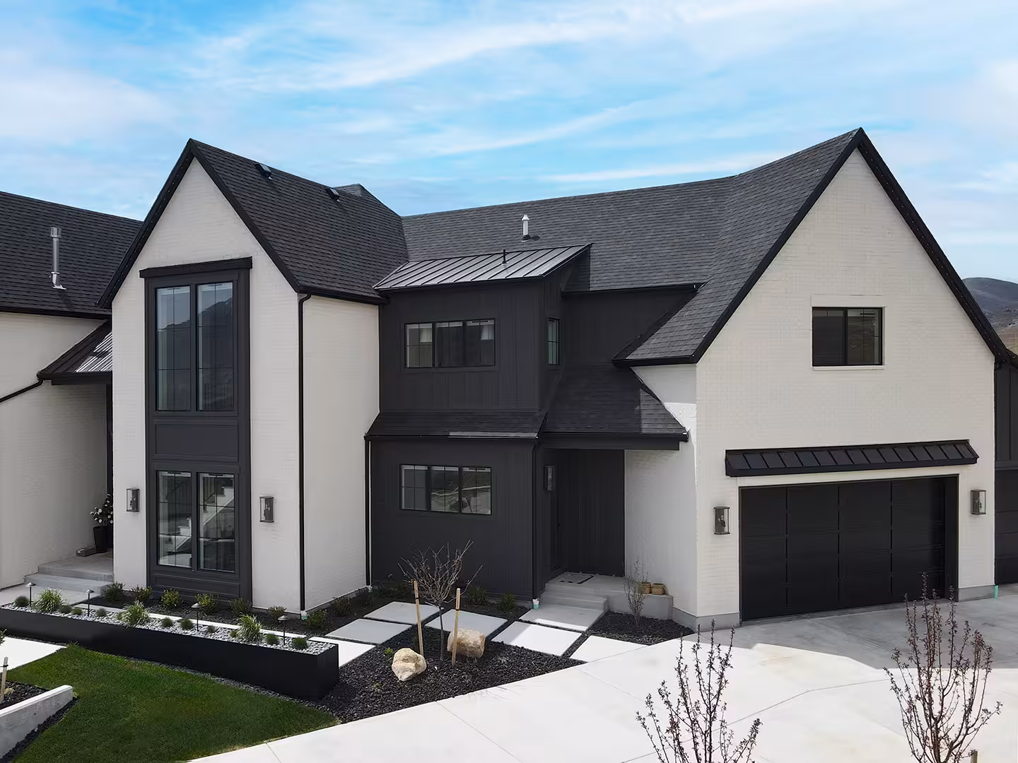 Front of the Syracuse home with white stucco, a black center section and a two-car garage