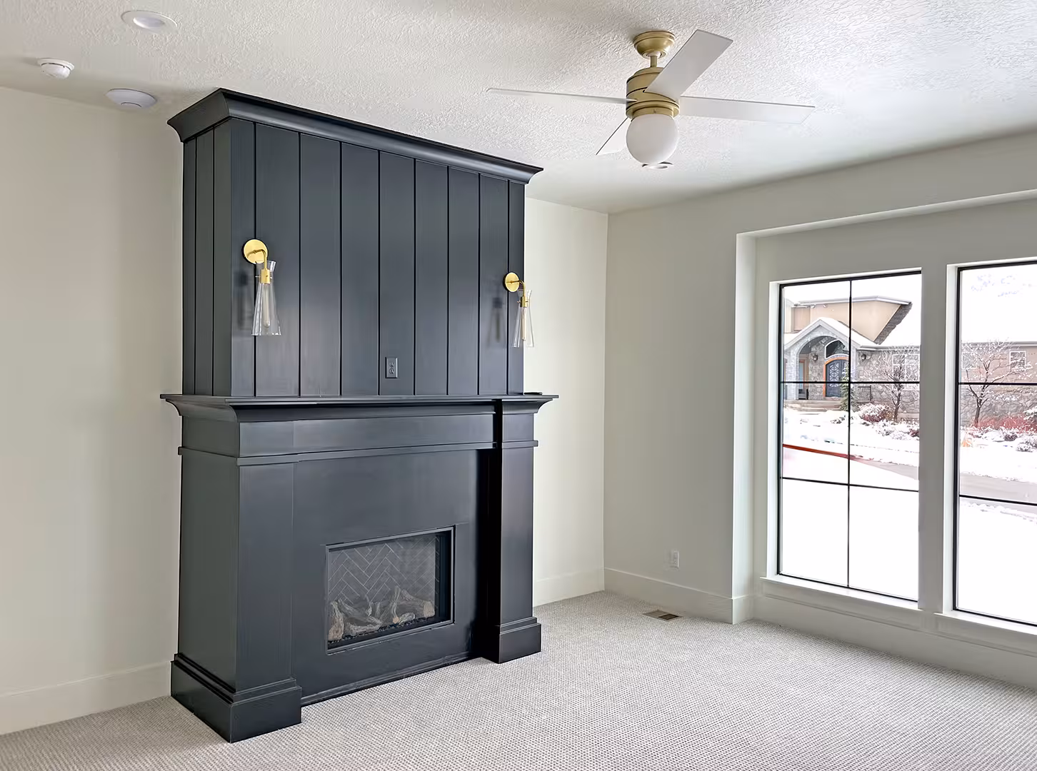 Bedroom in the Syracuse home with a black paneled fireplace and brass sconces