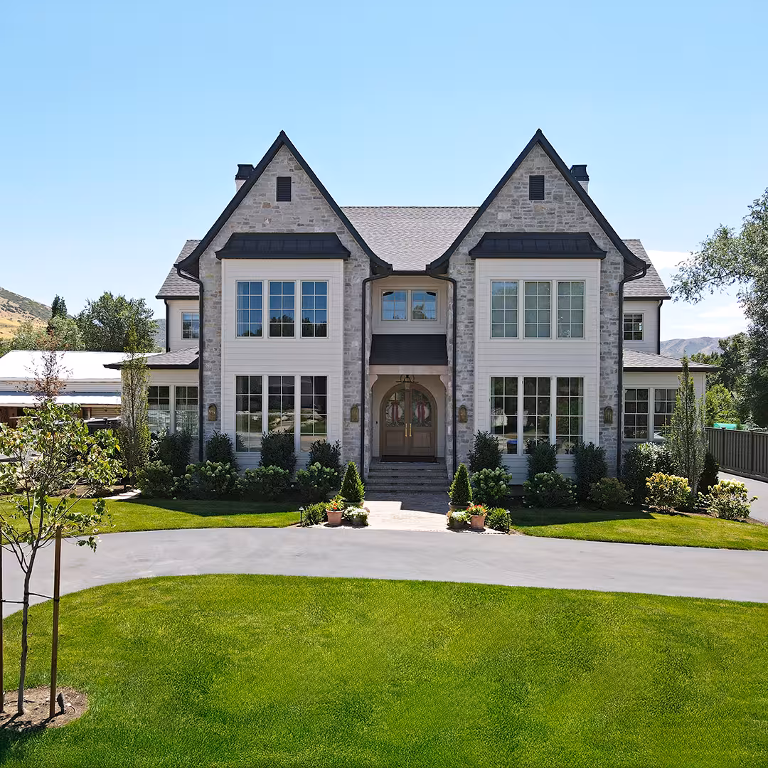 Front of the Vineyard home with stone twin gables, a wood arched door and a circular drive