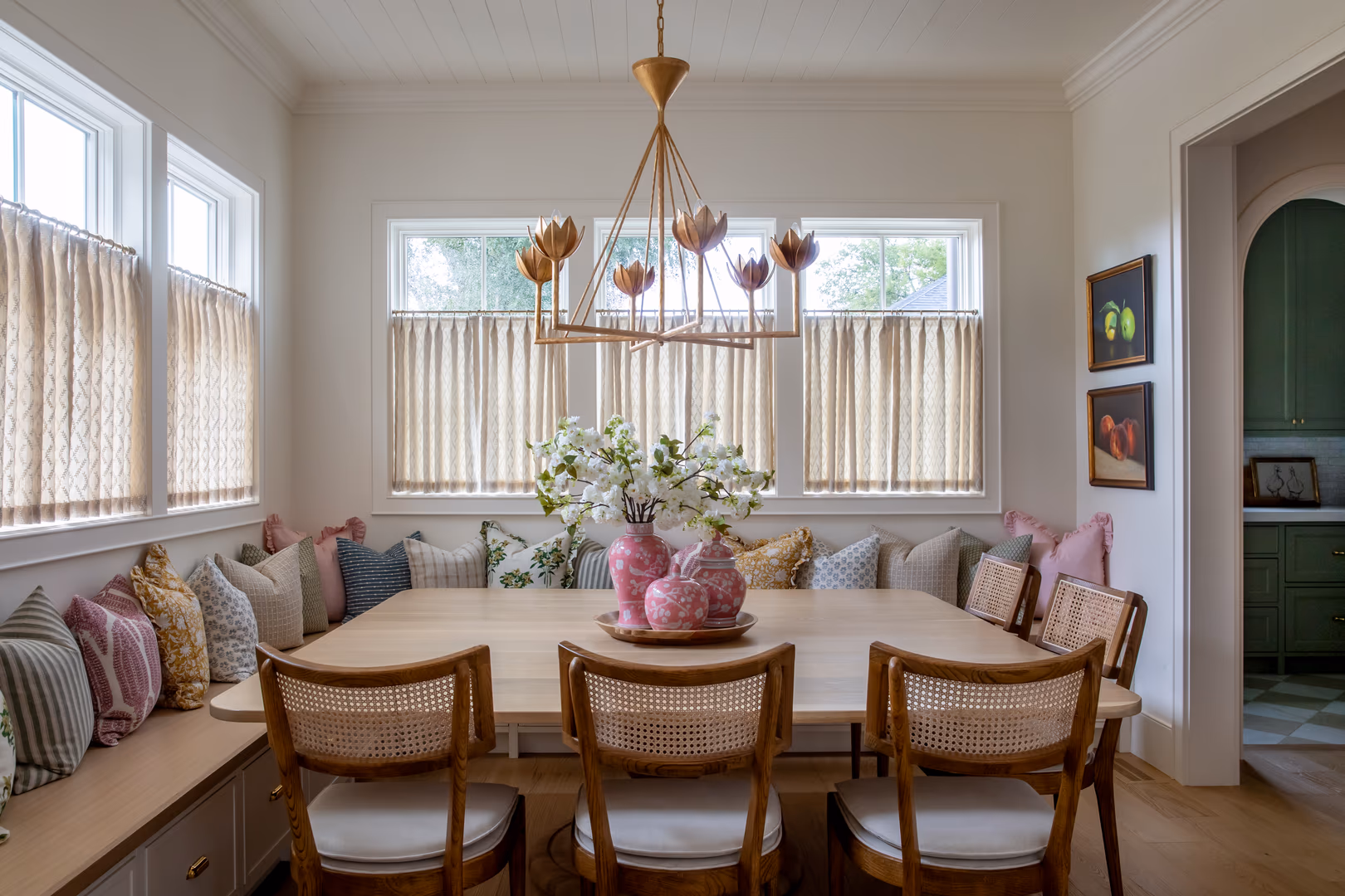 Breakfast nook in the Vineyard home with a built-in banquette, cafe curtains and a floral chandelier
