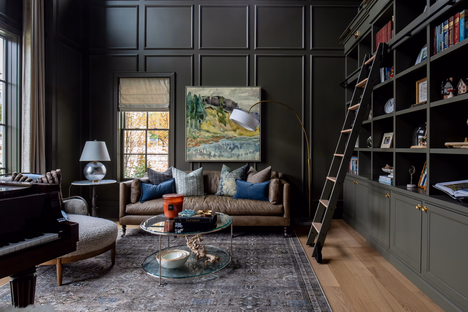 Vineyard home library with dark green paneling, a rolling ladder and a grand piano