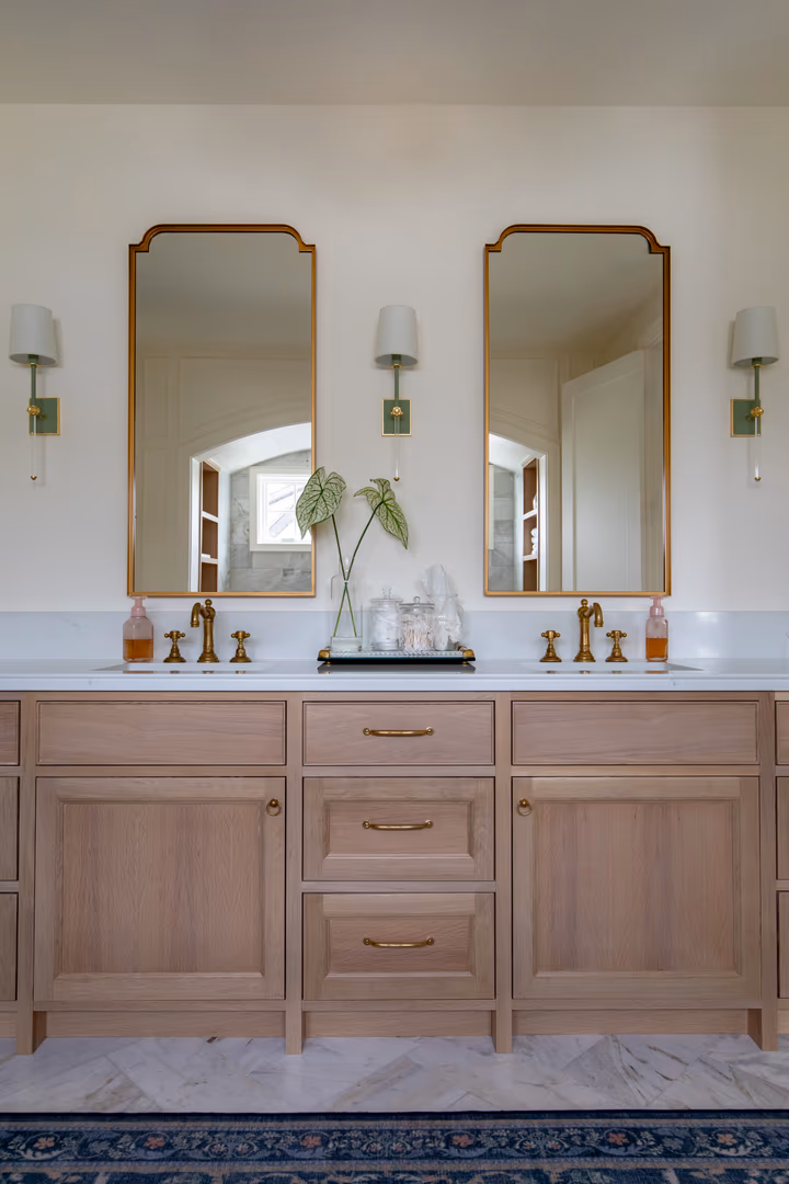 Vineyard bathroom with a light wood double vanity, brass mirrors and sconces