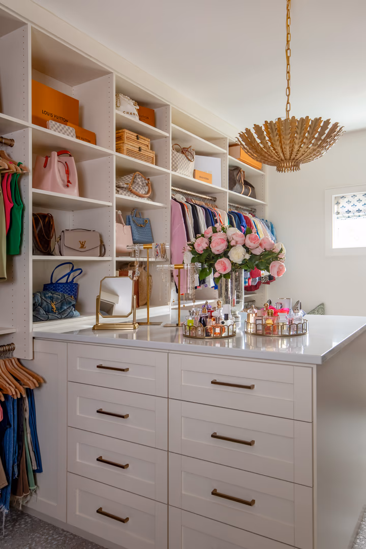Walk-in closet in the Vineyard home with an island dresser and a gold leaf pendant