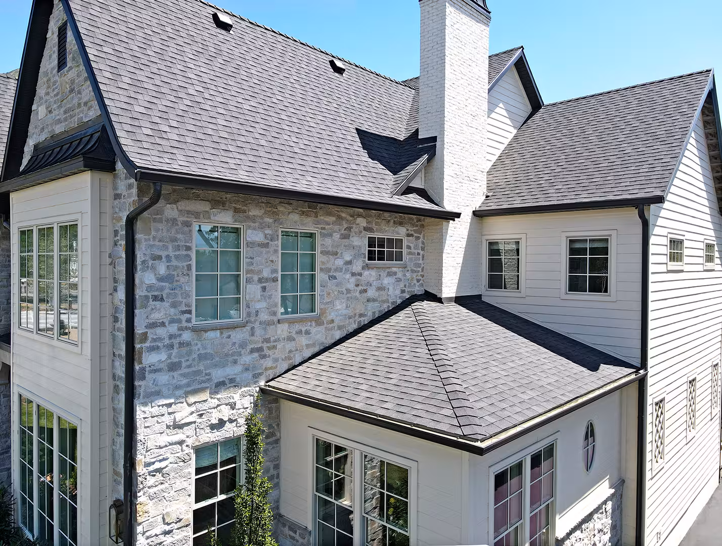 Close aerial view of the Vineyard home's stone walls, white siding and tall chimney