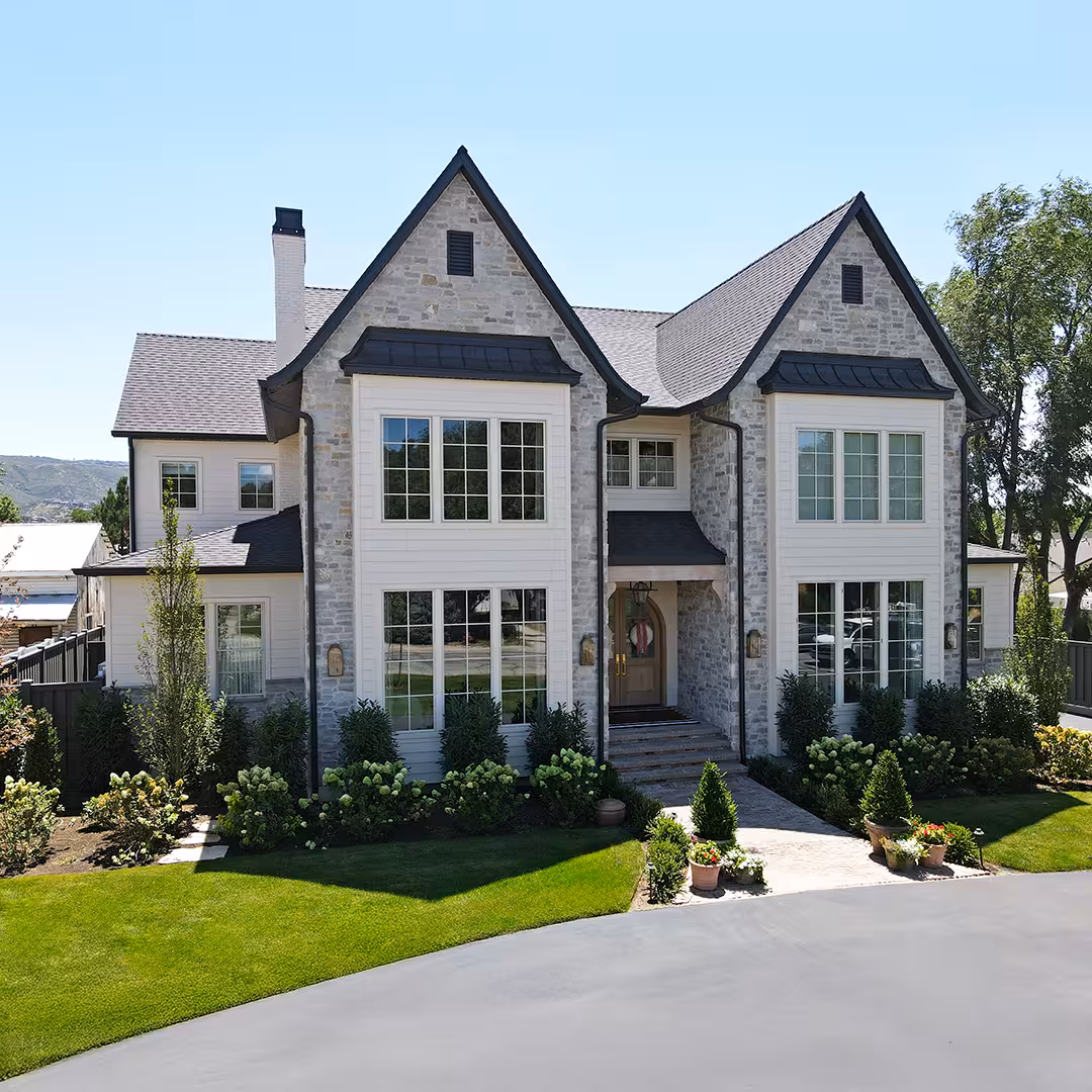 Vineyard home facade with stone gables, black metal window roofs and full front landscaping