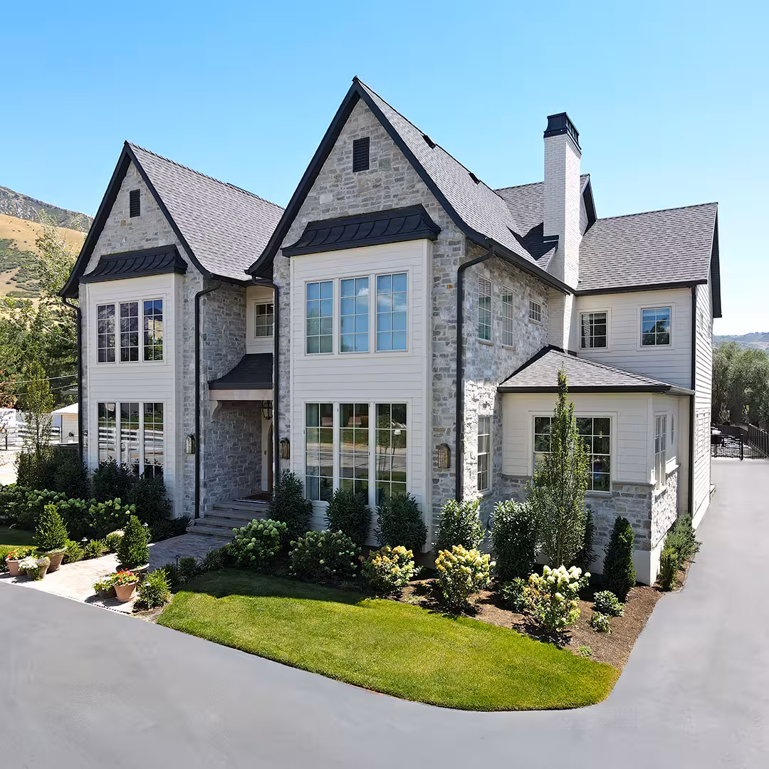 Corner view of the Vineyard home showing stone and white siding wings around a lawn