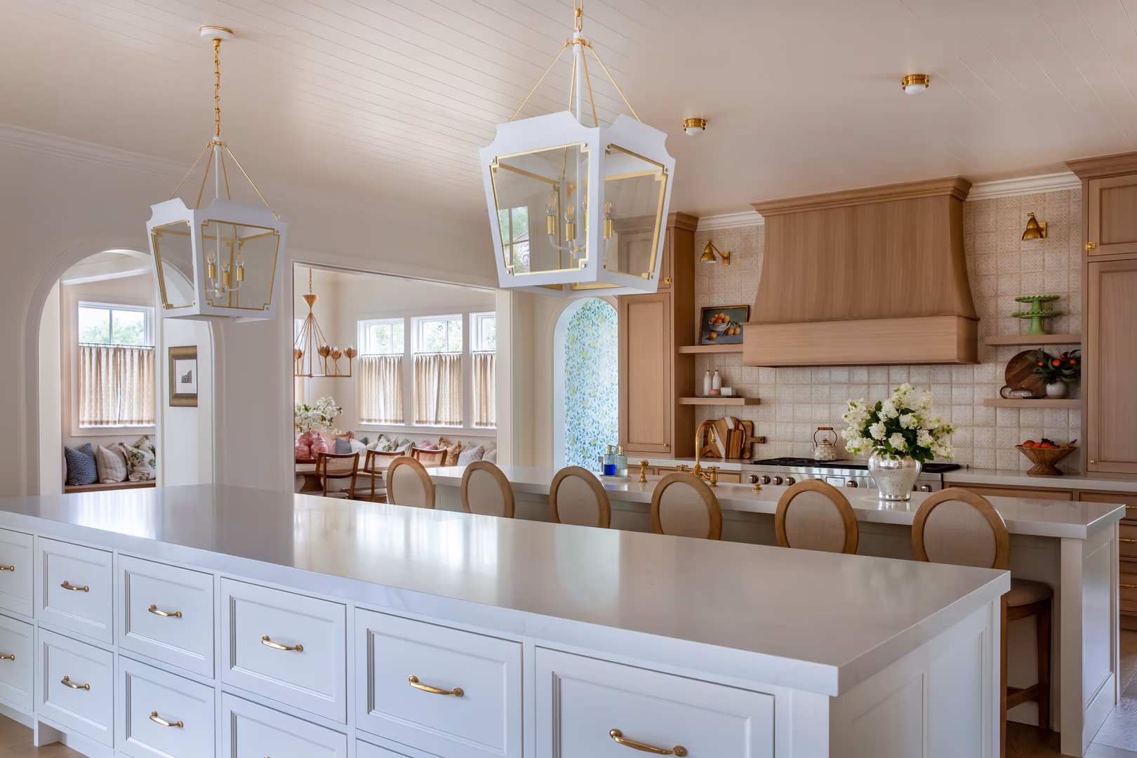 White kitchen island with brass pulls under lantern pendants in the Vineyard home