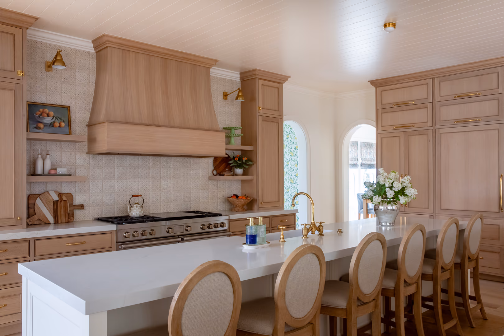 Vineyard kitchen range wall with a tapered wood hood, open shelves and oval-back stools