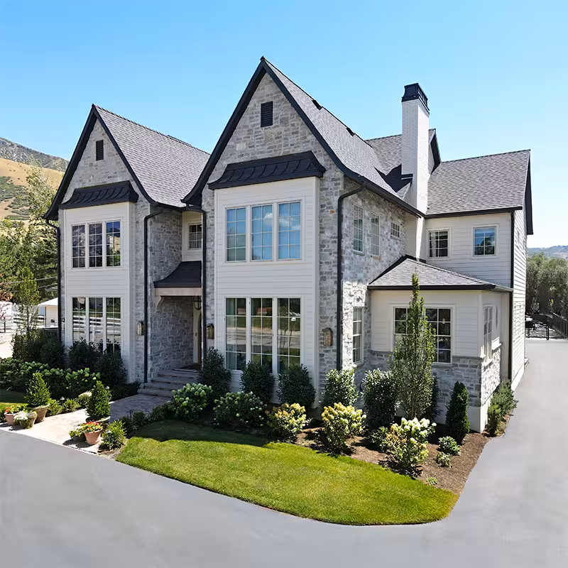 Custom home with stone gables, white siding and a landscaped front yard