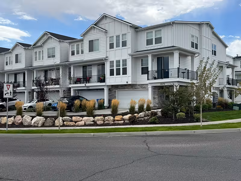 Three-story townhome building with white siding and private balconies