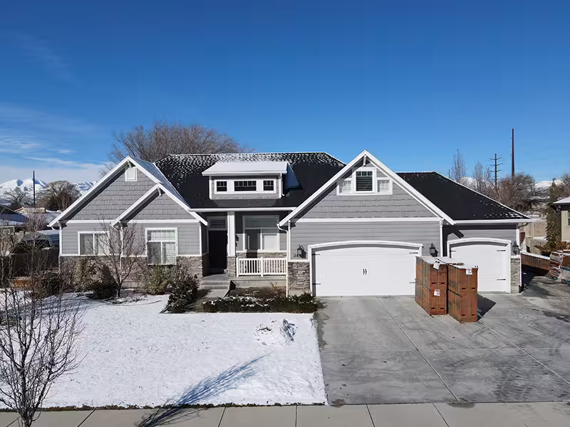 Before the remodel: gray-sided home with a two-car garage